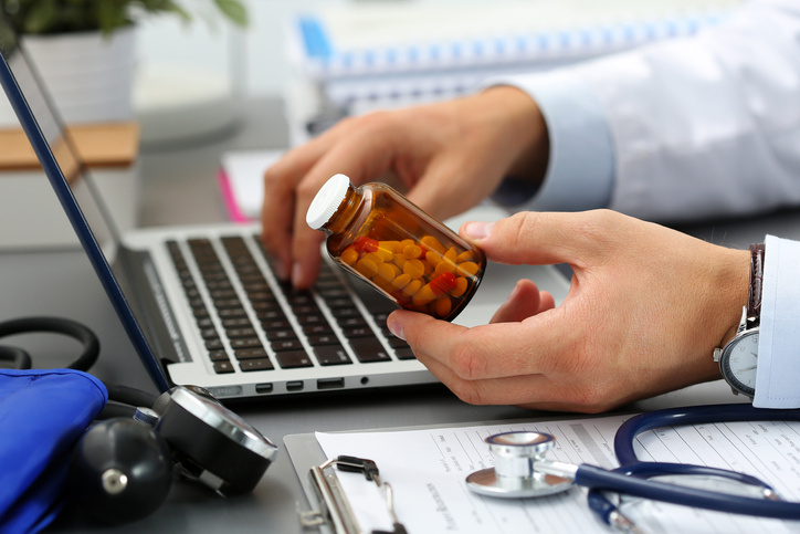 Male medicine doctor hands hold jar of pills Male medicine doctor hands hold jar of pills and type something on laptop computer keyboard. Panacea and life save, prescribing treatment, legal drug store, take stock, consumption statistics concept