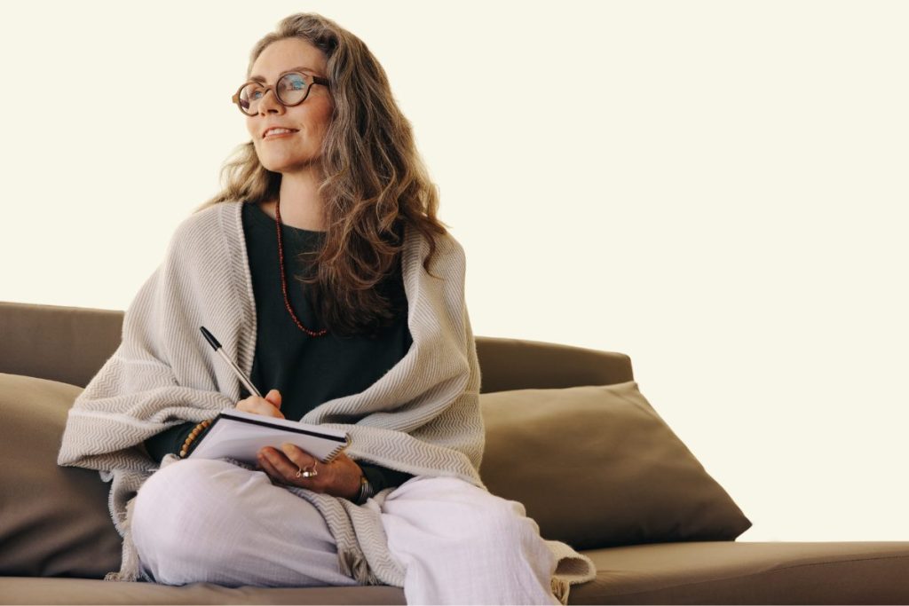 A mental health professional sitting calmly with a journal in hand, practicing self-reflection and mindfulness as part of her self-care routine.